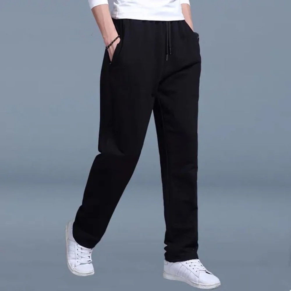 Vier heren joggingbroeken in grijs, zwart en blauw, gedragen met witte sneakers. Comfortabele sportkleding voor mannen, ideaal voor casual en sportief gebruik.