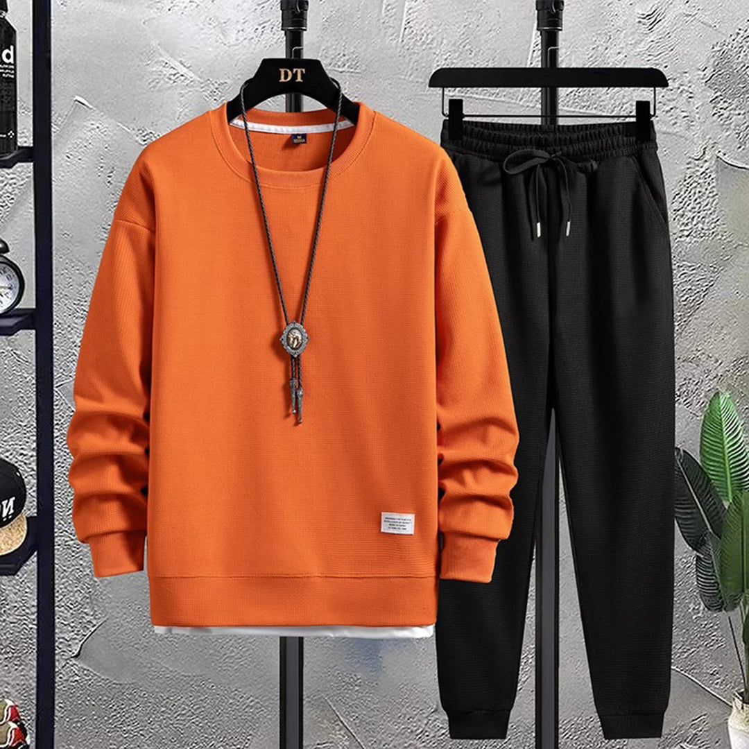 Heren joggingpak, beige trui en zwarte broek, casual sportkleding, comfortabele pasvorm, modieuze herenkleding, ideaal voor dagelijks gebruik.