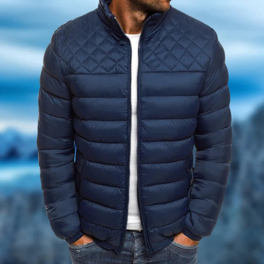 Blauwe gewatteerde herenjas, waterdicht, met ruitpatroon op de schouders. Verkrijgbaar in rood, zwart en blauw. Perfect voor wintermode.